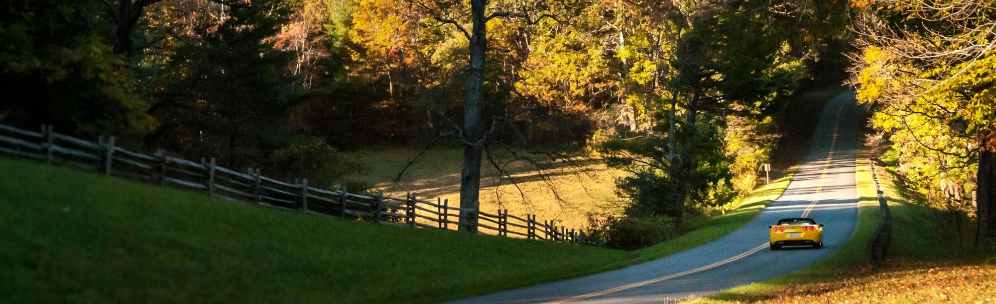 yellow corvette driving down a country road