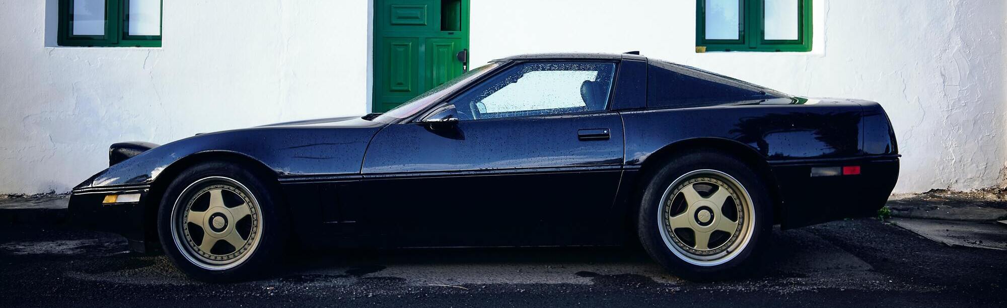 Black C4 Corvette with custom wheels in the rain