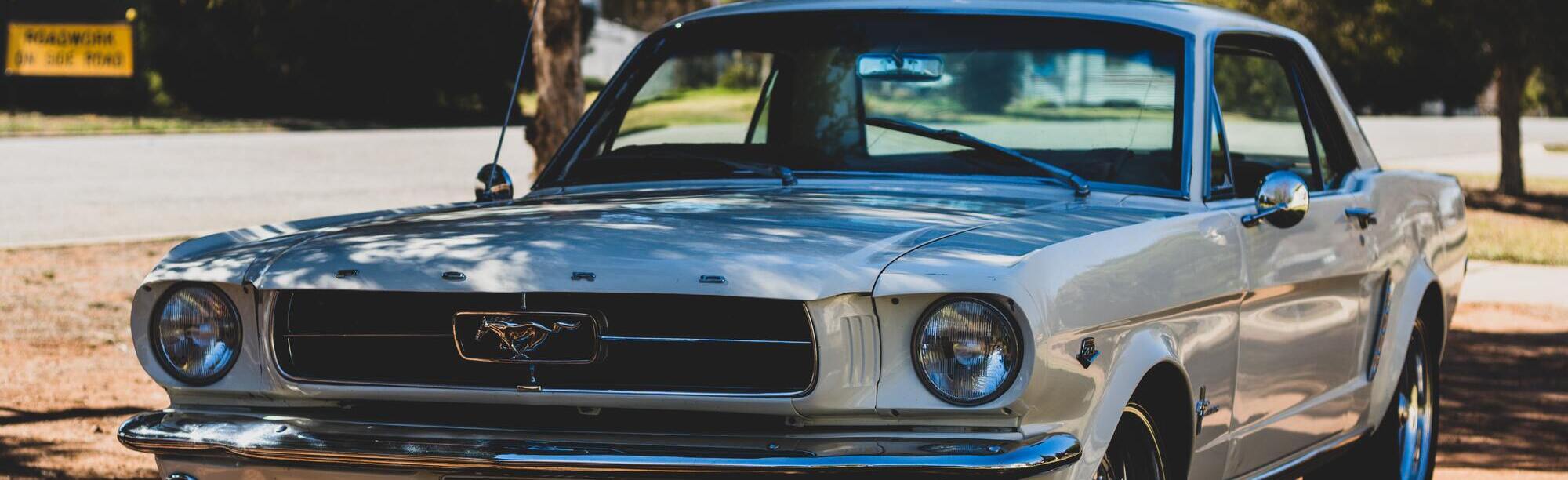 Classic white Ford Mustang coupe under the shade of a tree